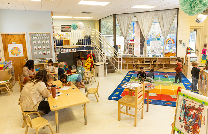The preschool room in the child development center provides a variety of experiences including arts and crafts, educational games and toys, as well as resources to explore reading and math. The room is spacious and bright, with large windows looking out over the playground area.