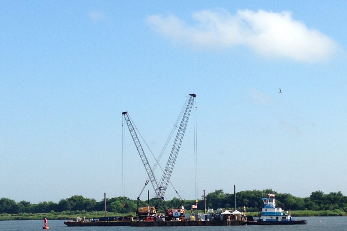 A barge with two large cranes anchored in the river.