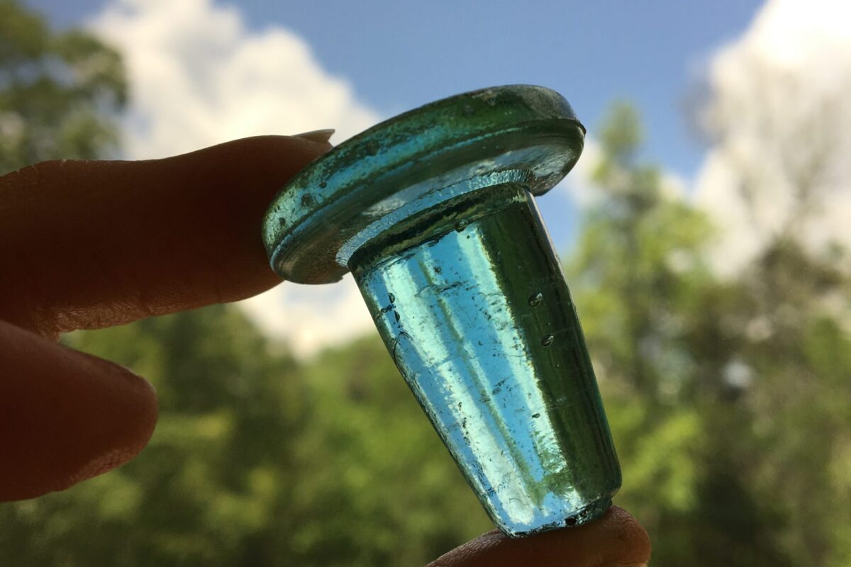 An aqua-colored glass bottle stopper.