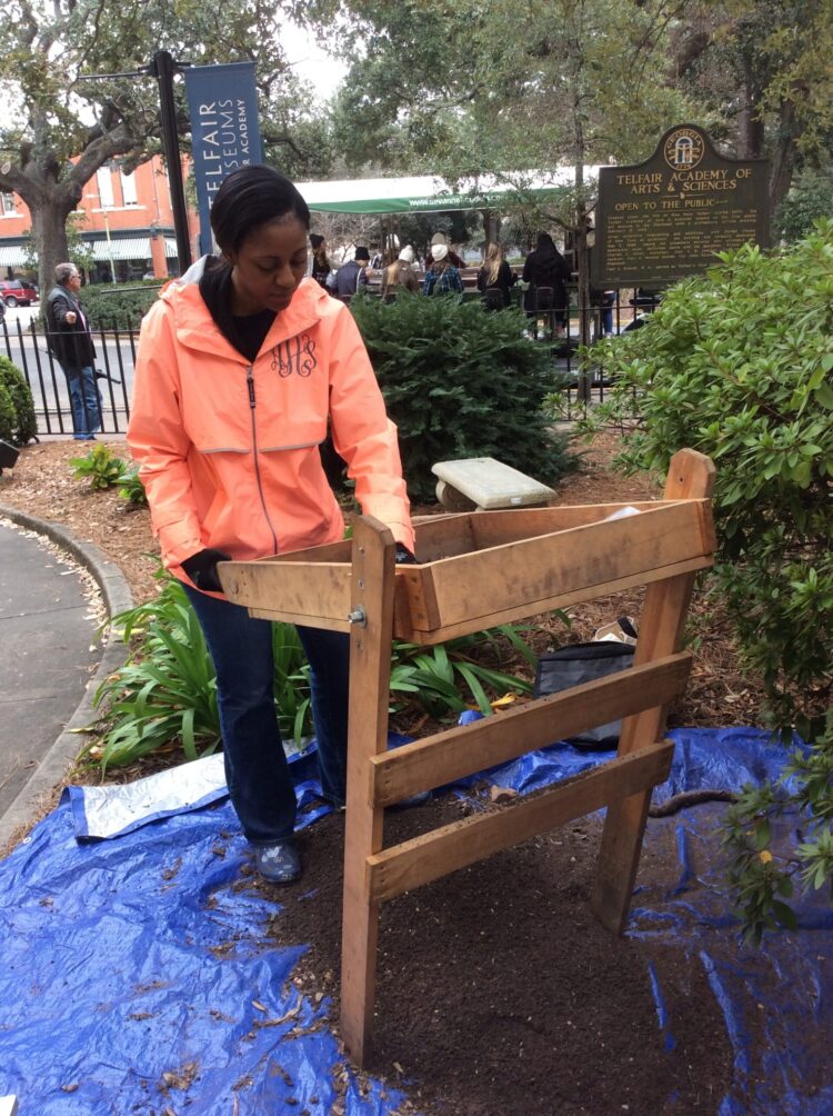 A woman screens artifacts in the front garden of the Telfair Museum.