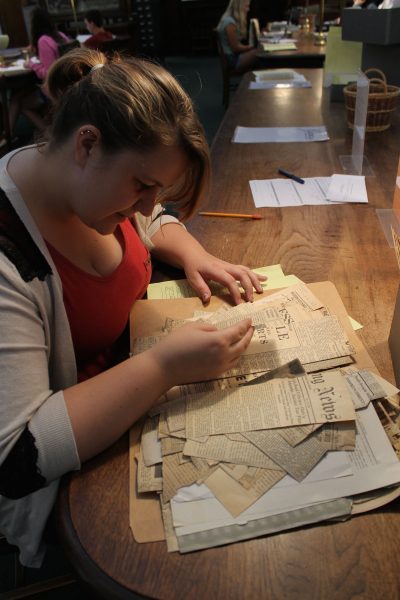 A student examines a file of old newspaper clippings.