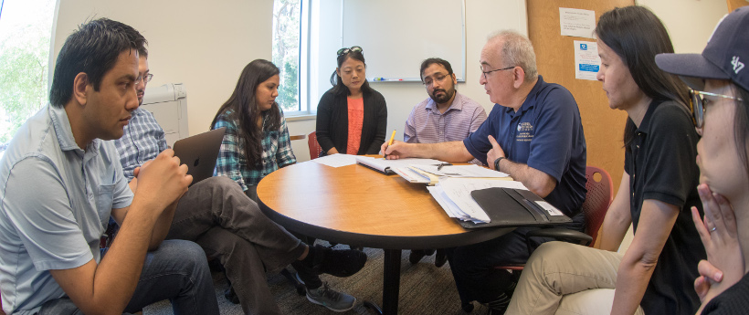 students and faculty siting around a table meeting