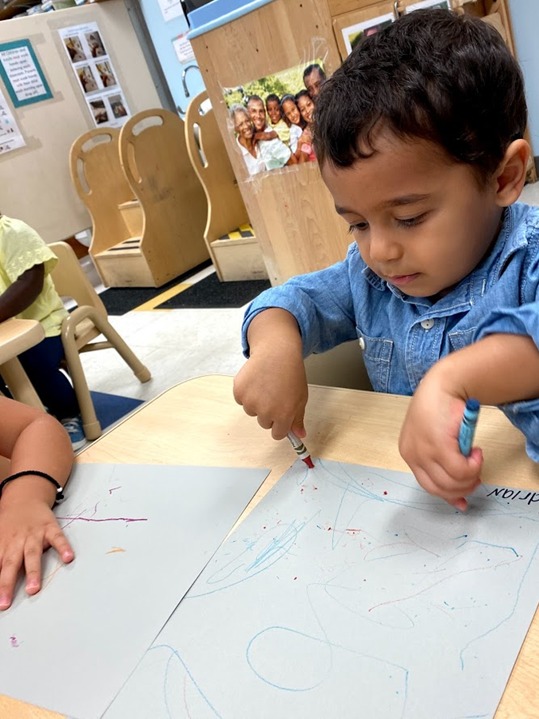 A preschool child draws with crayons.