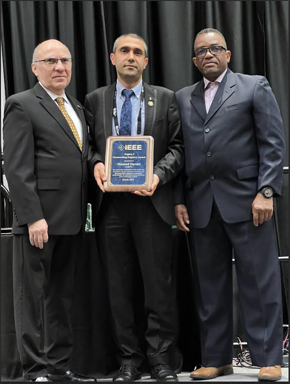 Three men in suits, one holding an award plaque.