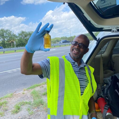A community participant holds up a small bottle of water used for chemical analysis