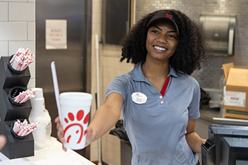 A server at Chik-fil-a gives a customer a drink order.