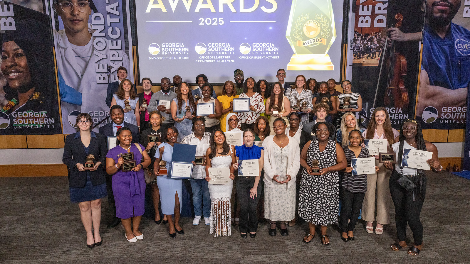 The recipients of the 2025 Eagle Excellence Awards pose for a group photo onstage after the ceremony.