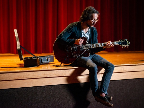 A Georgia Southern music student practices with a Gretsch guitar on a stage.