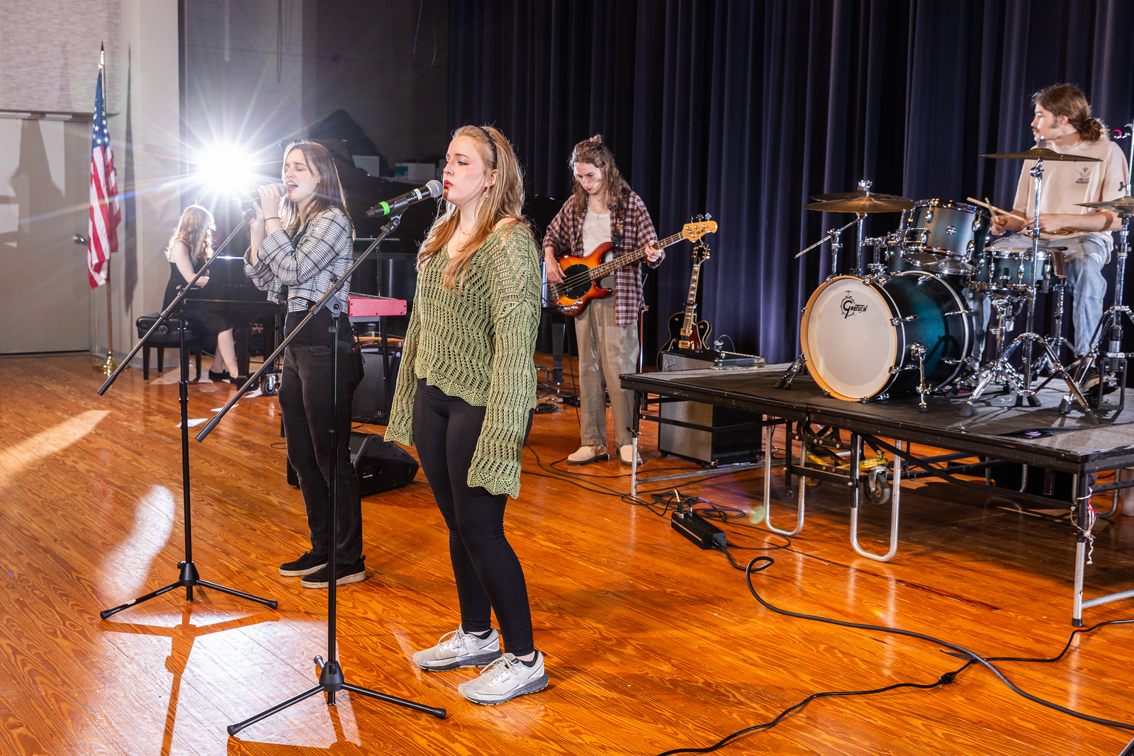 Advanced Commercial Ensemble members rehearse on stage for Georgia Southern with instruments and drum set and vocals.