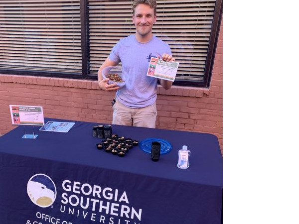 An OLCE volunteer mans a table at an event.