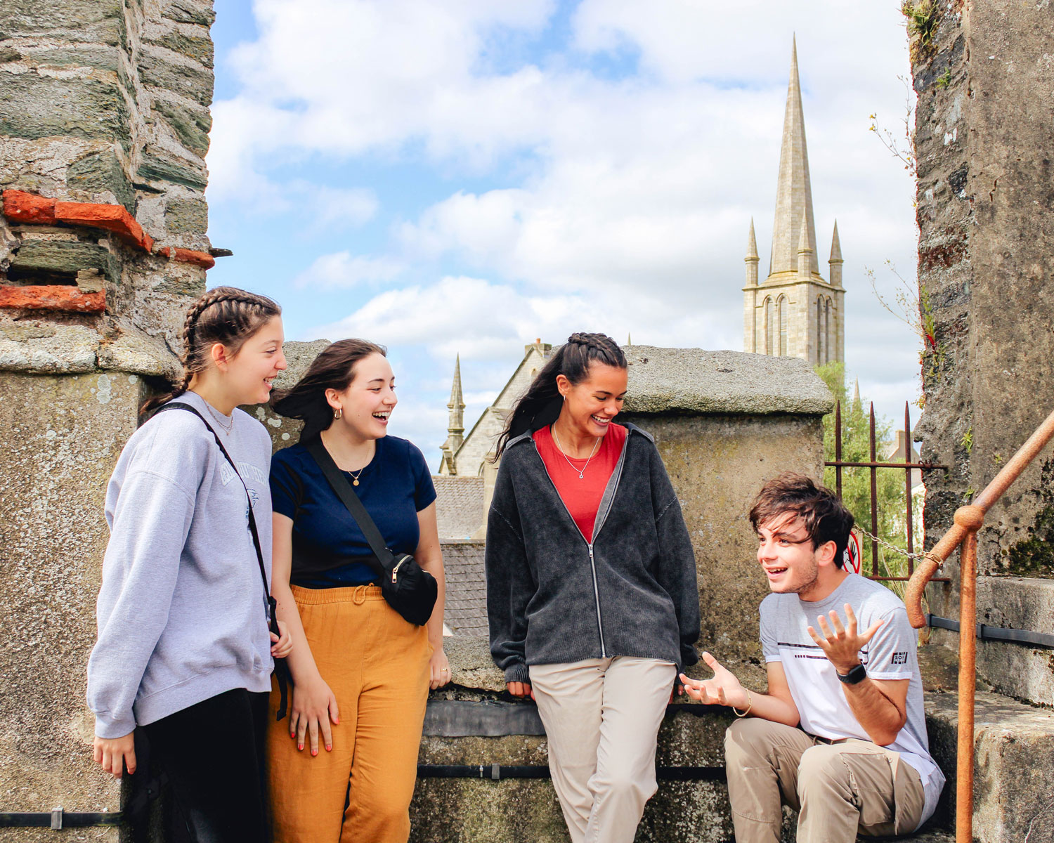 A group of Georgia Southern students sitting at a historical site talking, with a cathedral in the foreground.