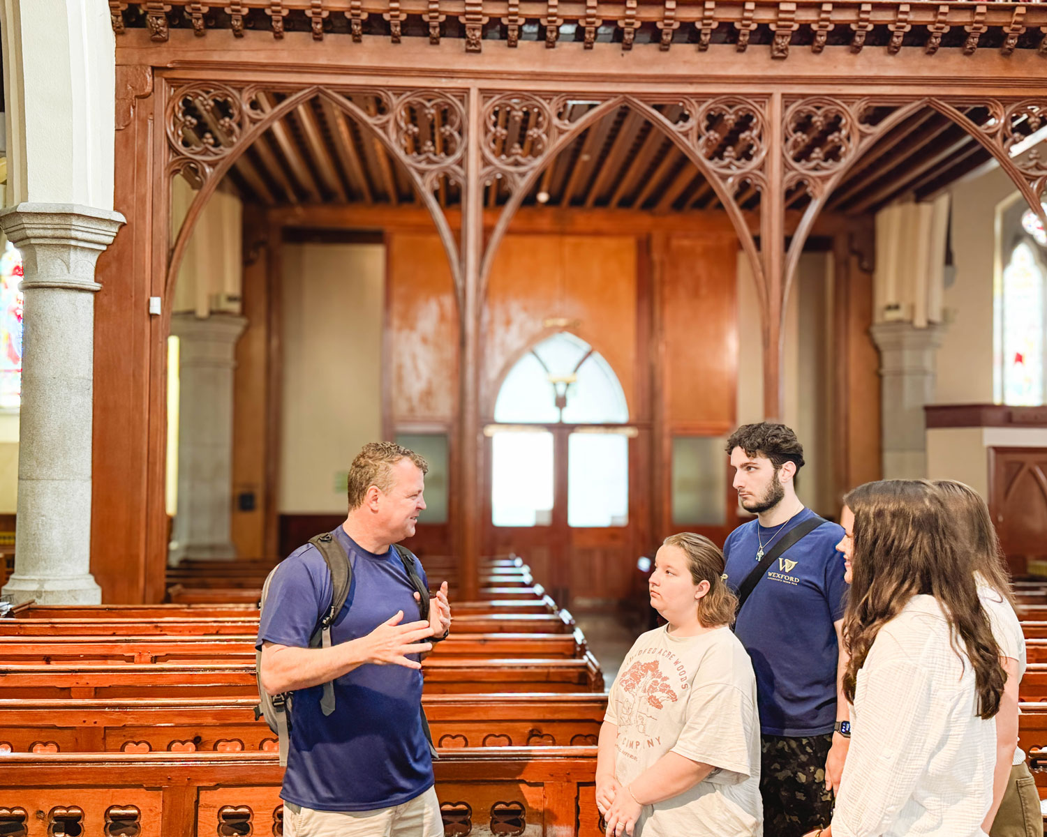 A Wexford guide talking to a small group of students inside a cathedral.