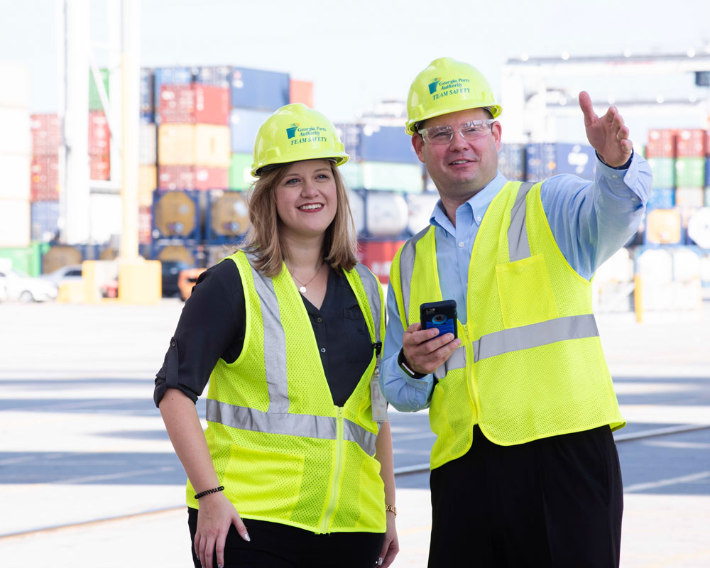 Wearing hi-vis vests and hard hats, a student and instructor from Georgia Southern's Georgia Southern Department of Logistics and Supply Chain Management point toward a project.