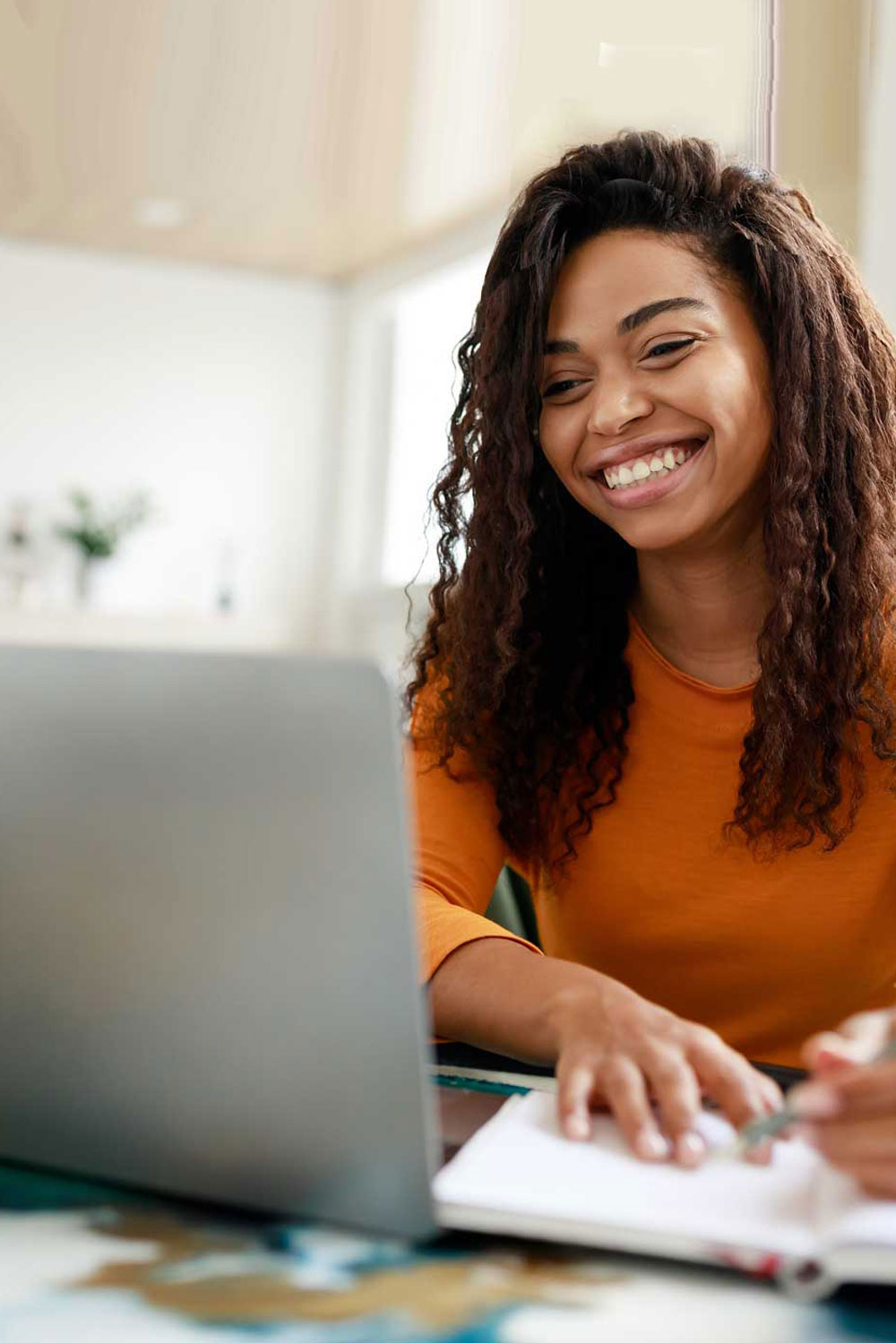 Young African-American female student smiling with laptop and notebook.