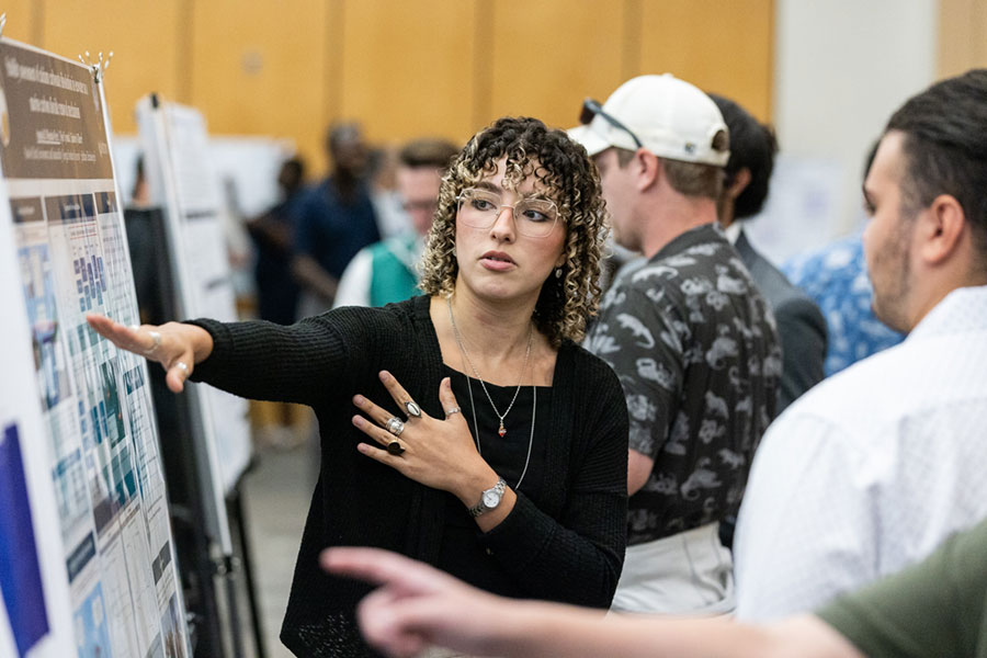 Women in curly hair explaining her research in an expo