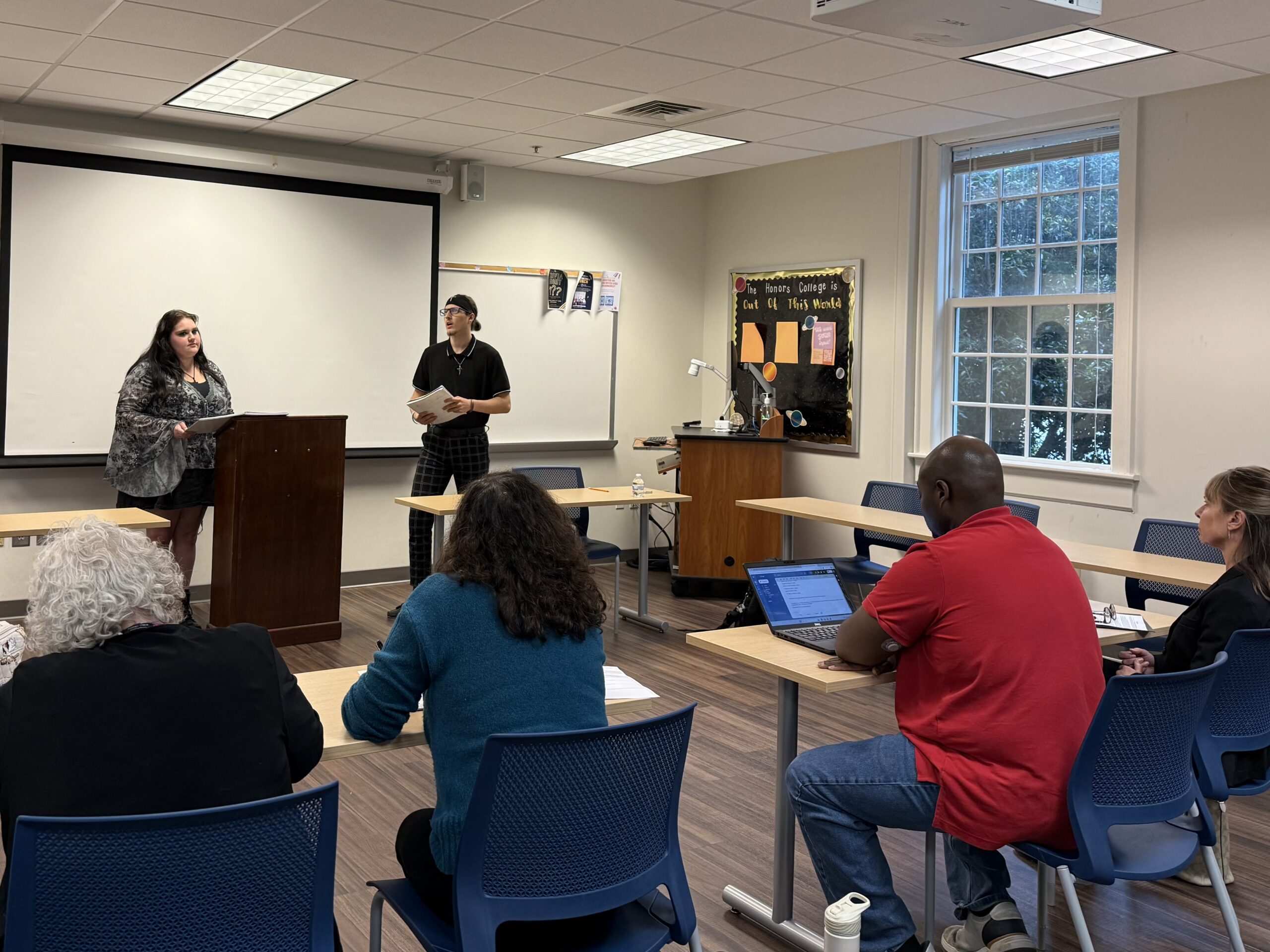 Two students debate each other while standing in front of a judges panel