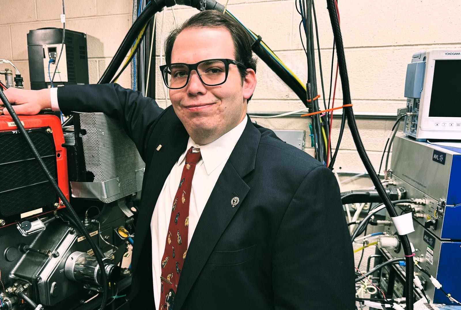 Brad Willis is standing in front of machinery in a lab.