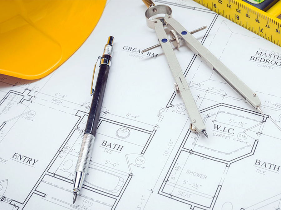 Architectural floor plans laying flat with a drafting compass, mechanical pencil, and yellow hard hat.